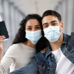 planning your trip - COVID-19 Travels. Happy Arab Couple In Medical Mask Taking Selfie In Airport
